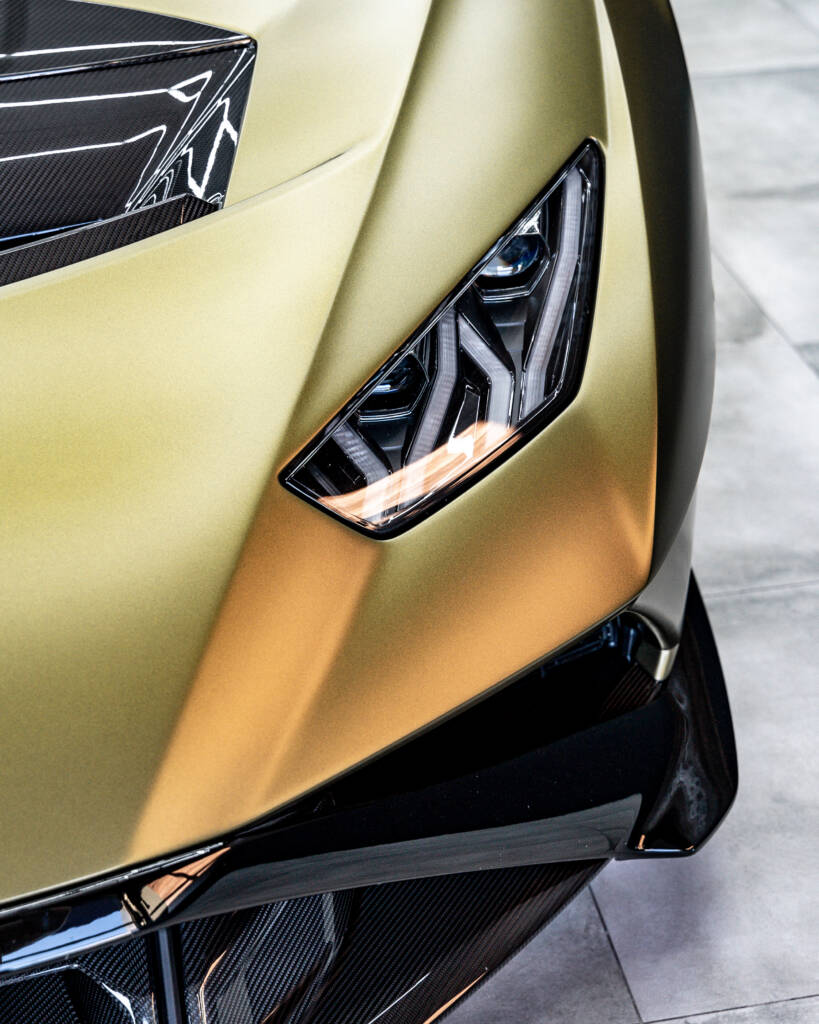 Detailaufnahme des aggressiven LED-Scheinwerfers eines mattgold folierten Lamborghini.